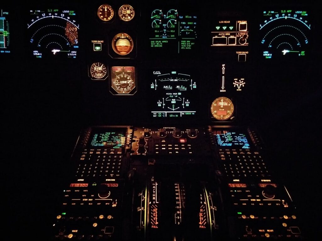 Close-up view of an aircraft cockpit illuminated at night with various gauges and instruments.